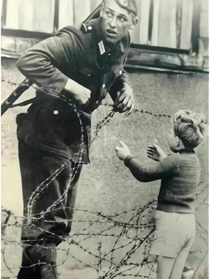 东德边防士兵徒手拉开铁丝网帮助小男孩穿越边境